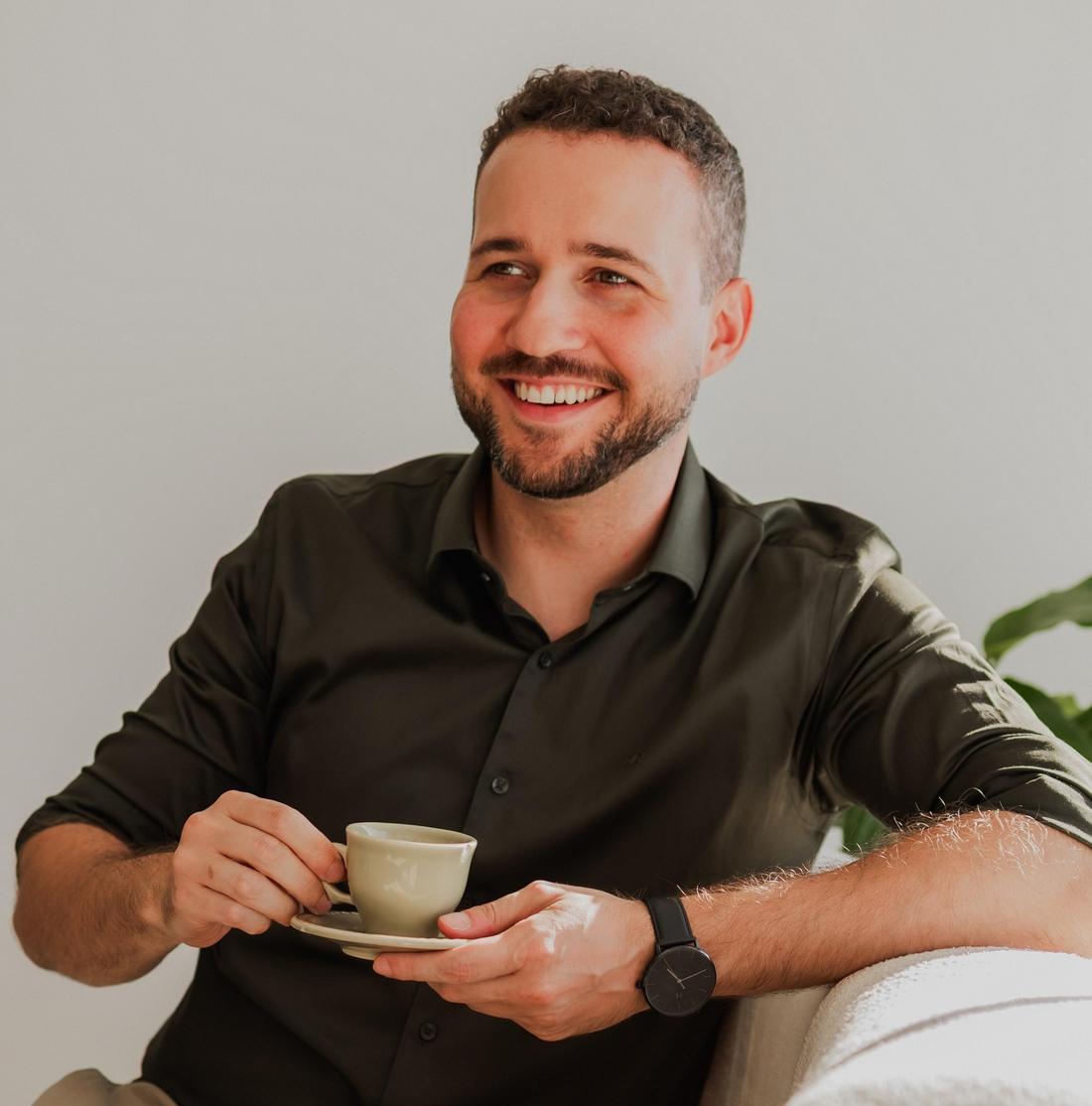 Lucas Voltolini sorrindo, com uma xícara de café