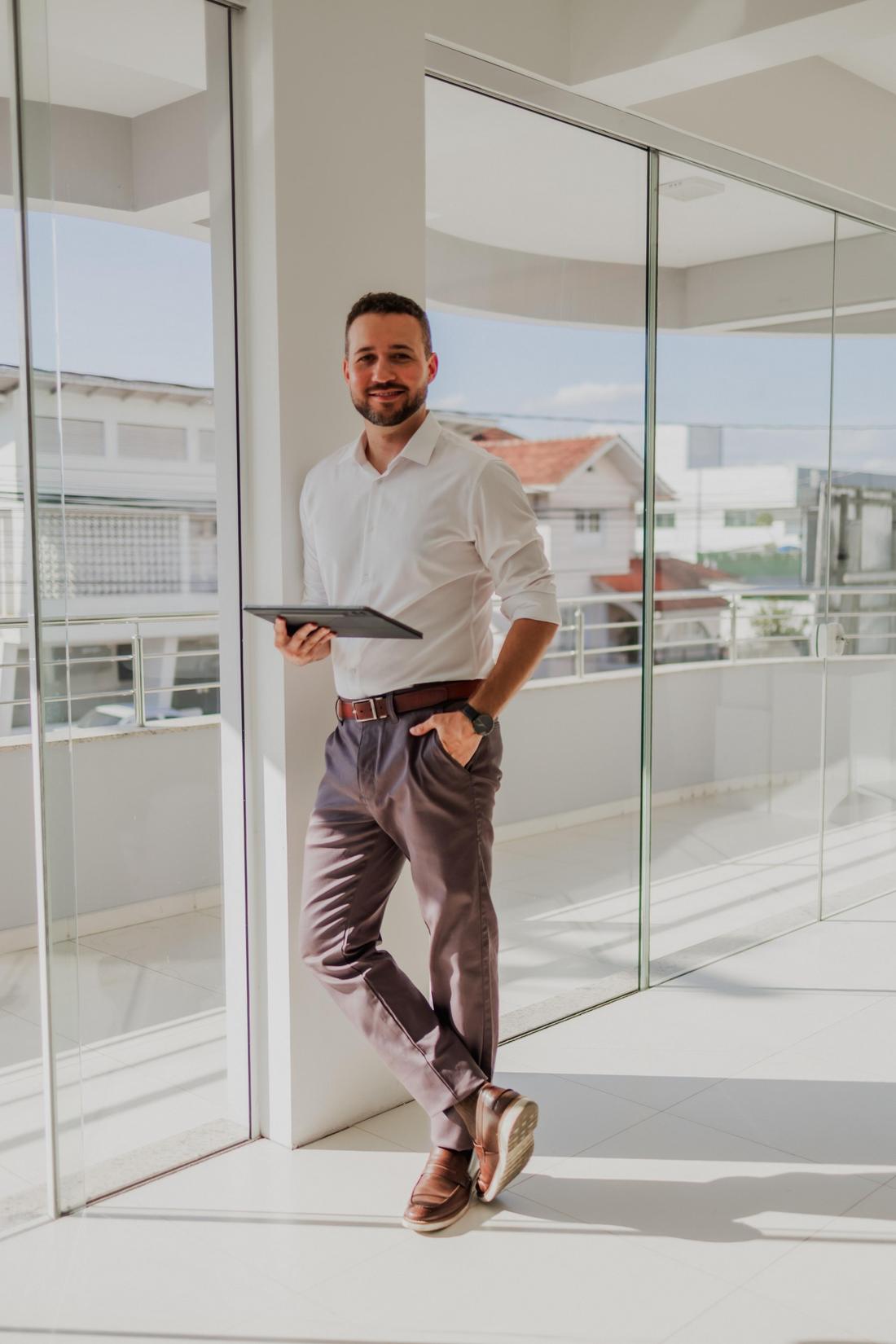 Lucas Voltolini, consultor de compras, em um corredor corporativo com um tablet nas mãos